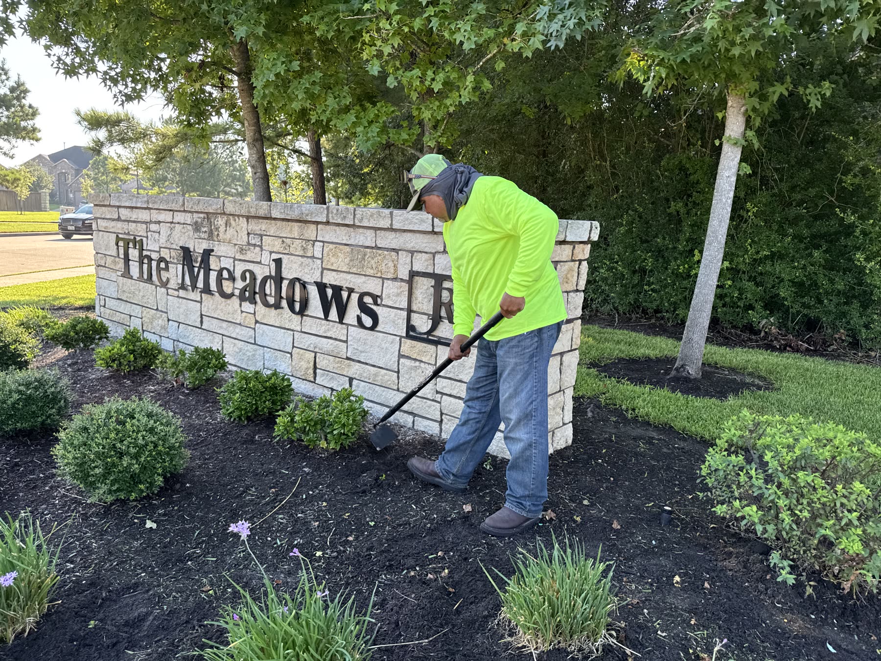 Crew edging mulch beds at community entrance