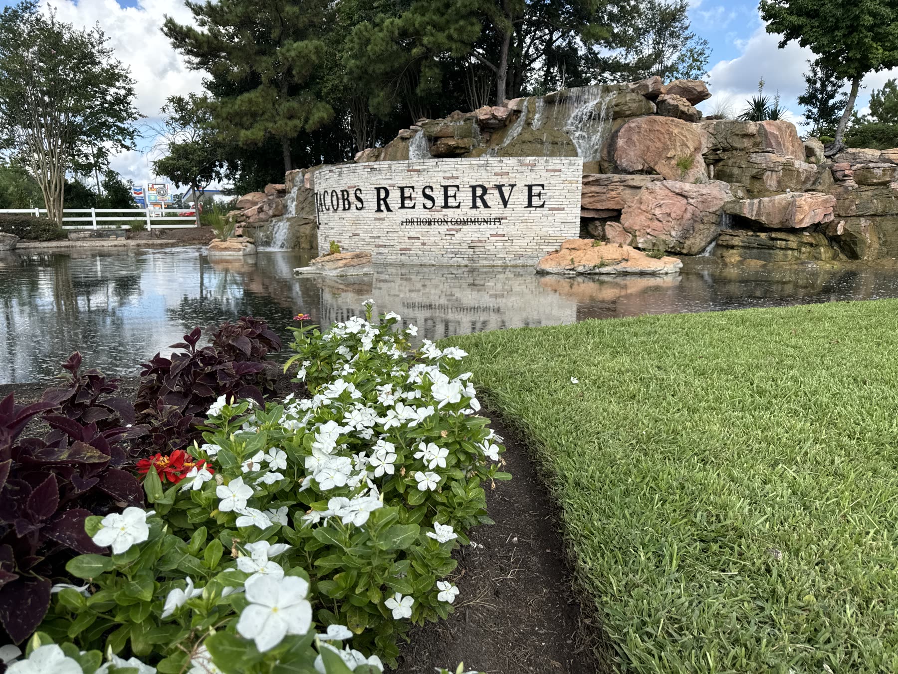 HOA community entrance monument with waterfall and seasonal flowers